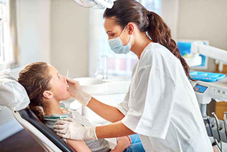 A dental professional discusses orthodontic models with a patient in a bright dental office.